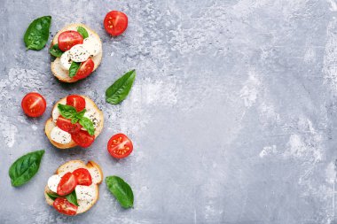 Üzerinde gri ahşap masa Bruschetta mozzarella peyniri, domates ve fesleğen yaprakları