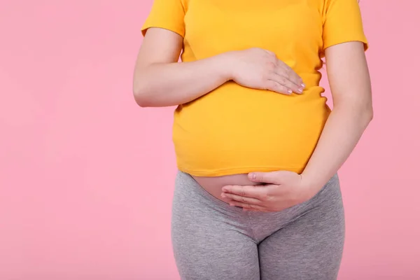 ピンクの背景の妊娠中の女性 — ストック写真