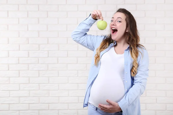 Hermosa Mujer Embarazada Comiendo Manzana Verde Sobre Fondo Pared Ladrillo — Foto de Stock