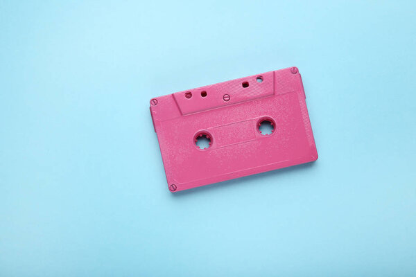 Pink cassette tape on blue background