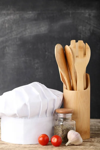調理器具と木製のテーブルの上の野菜とシェフの帽子 — ストック写真