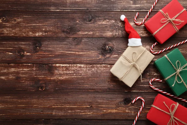 Gift boxes with santa claus hat and candy cane on brown wooden table