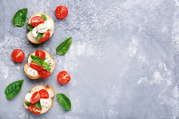 Bruschetta Com Mussarela Tomates Folhas Manjericão Sobre Mesa Madeira Cinza — Fotografia de Stock