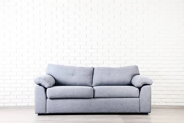 レンガ壁の背景にモダンなグレーのソファー — ストック写真