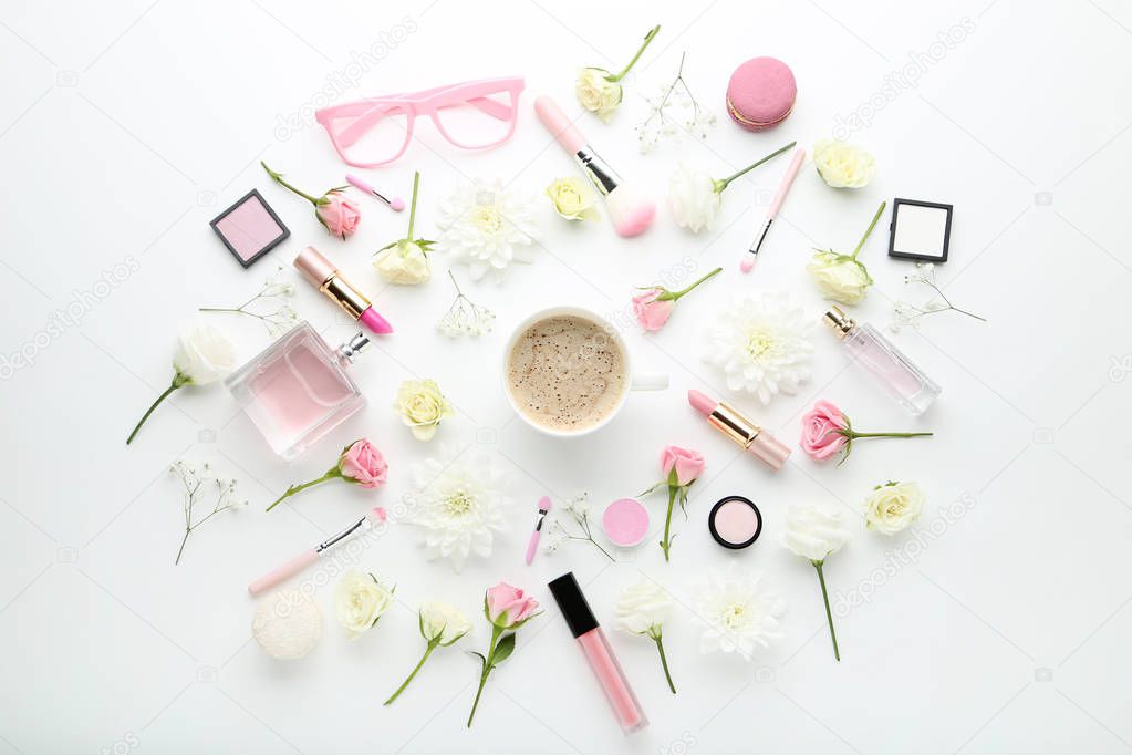 Flowers with cup of coffee and makeup cosmetics on white background