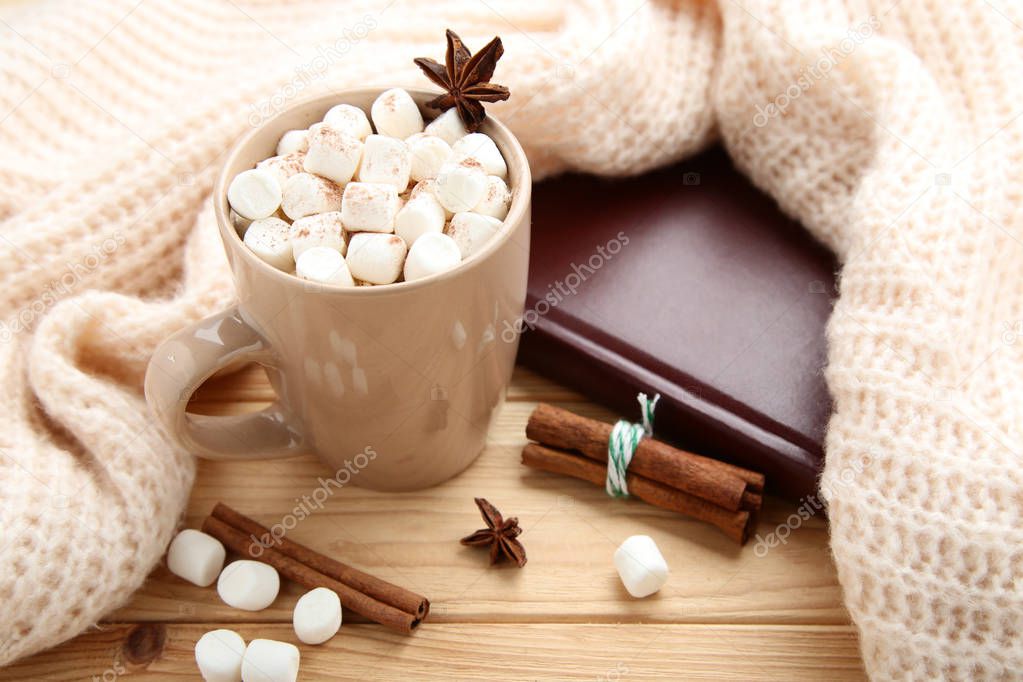 Cappuccino with marshmallows and knitted scarf on wooden table