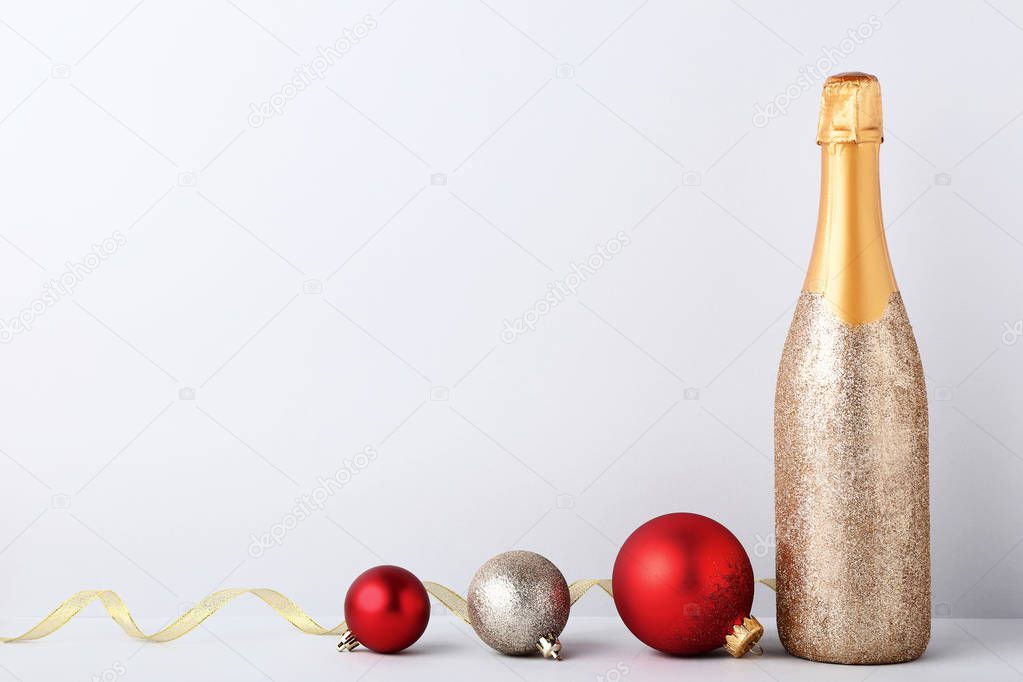 Decorated champagne bottle with christmas baubles on grey background
