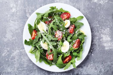 Roka salatası yapraklar, domates ve gri ahşap masa üzerinde yumurta