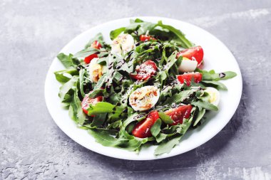 Roka salatası yapraklar, domates ve gri ahşap masa üzerinde yumurta