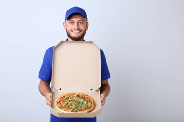 Gri arka plan üzerine karton kutu içinde pizza teslimi adam