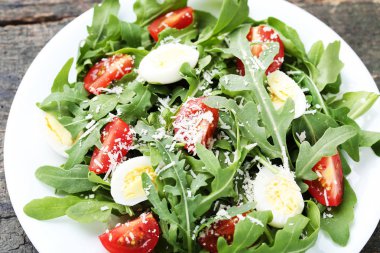 Roka salatası yapraklar, domates ve gri ahşap masa üzerinde yumurta