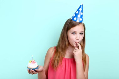 Doğum günü şapkalı cupcake mum ile nane arka planda tutan genç kız