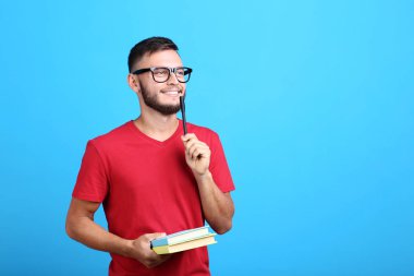 Kitap ve kalem mavi arka plan ile bardaklarda genç adam