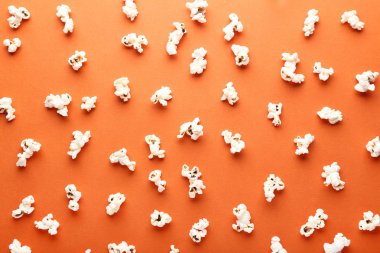Turuncu arka plan üzerinde dağınık tuzlu popcorn