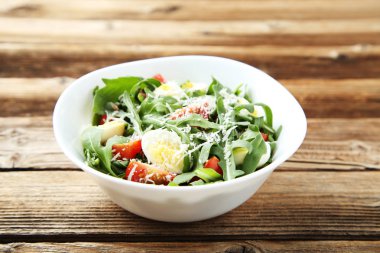 Roka salatası yapraklar, domates ve yumurta üzerinde kahverengi ahşap masa