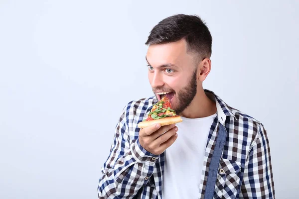 Jonge Man Eten Pizza Een Grijze Achtergrond — Stockfoto