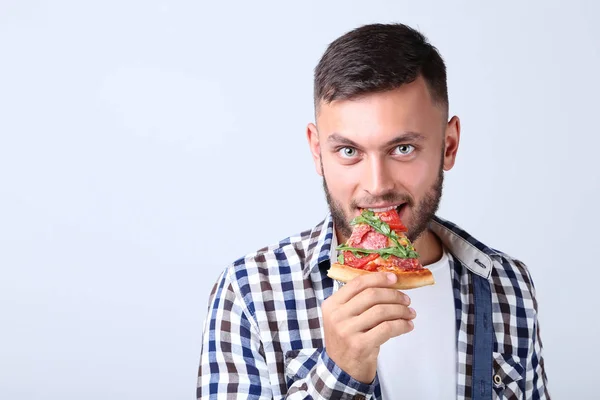 Jonge Man Eten Pizza Een Grijze Achtergrond — Stockfoto