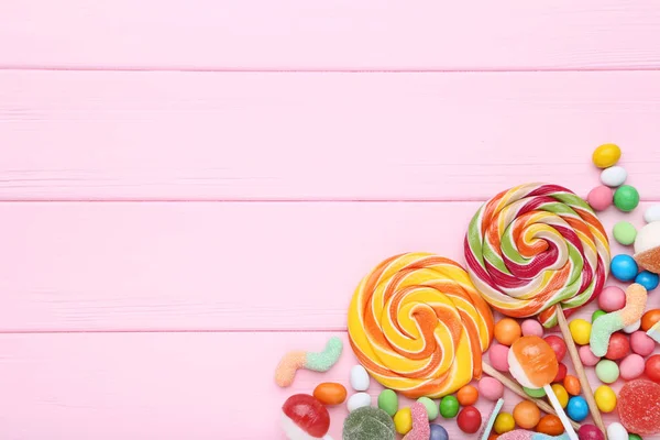 粉红色木桌上的甜糖果和棒棒糖 — 图库照片