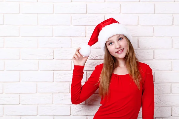 年轻的女孩在圣诞老人帽子在砖墙背景 — 图库照片