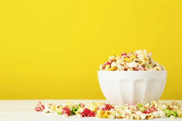 Colorful popcorn in bowl on yellow background