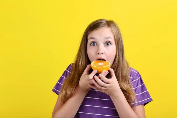 Chica Joven Comiendo Fruta Naranja Sobre Fondo Amarillo — Foto de Stock