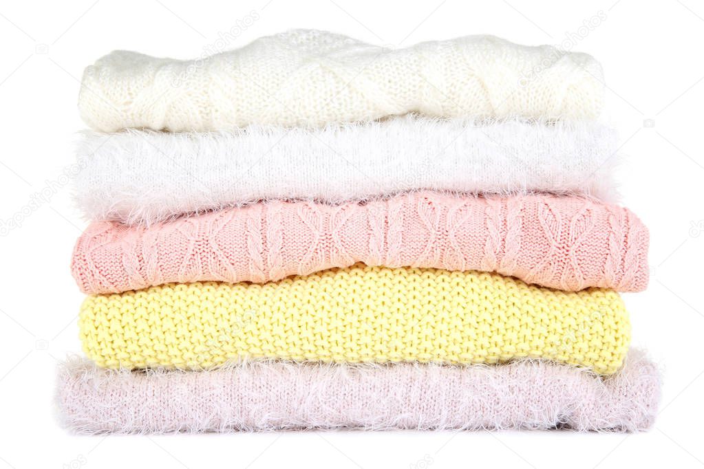 Stack of folded sweaters on white background