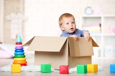 Karton kutunun içinde evde oturan erkek bebek