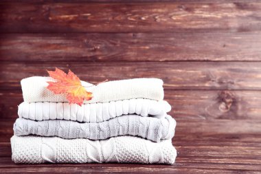 Akçaağaç yaprağı ahşap masa üzerinde katlanmış kazak yığını