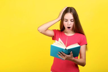 Genç kız sarı zemin üzerine kitap okuma şaşırttı