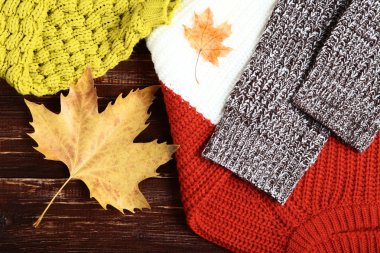 Kahverengi ahşap masa üzerinde sonbahar yaprakları ile örme kazak