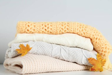 Gri arka plan üzerinde yığın katlanmış kazak ile sonbahar yaprakları