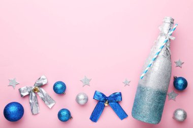 Pembe bir arka plan üzerinde Noel süslemeleri ile şampanya şişesi