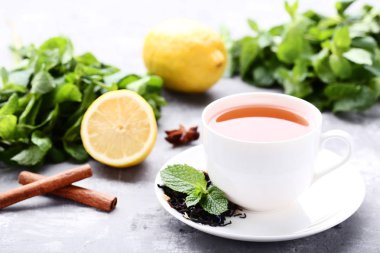 Çay nane ile yapraklar, limon ve tarçın sopa üzerinde gri ahşap masa