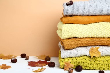 Biege'e arka plan üzerinde yığın katlanmış kazak meşe palamutları, kestane ve sonbahar yaprakları