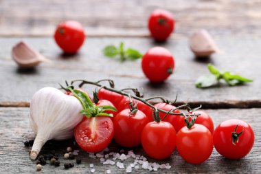 Kiraz domates fesleğen yaprağı, sarımsak ve baharat gri ahşap tablo