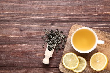 Kuru yaprakları ve kahverengi ahşap masa üzerinde limon ile çay