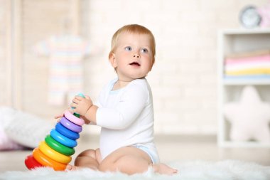 Evde halı üzerinde oturan oyuncaklarla erkek bebek