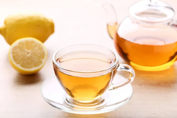 レモンと木製のテーブル上のティーポットと紅茶のカップ — ストック写真