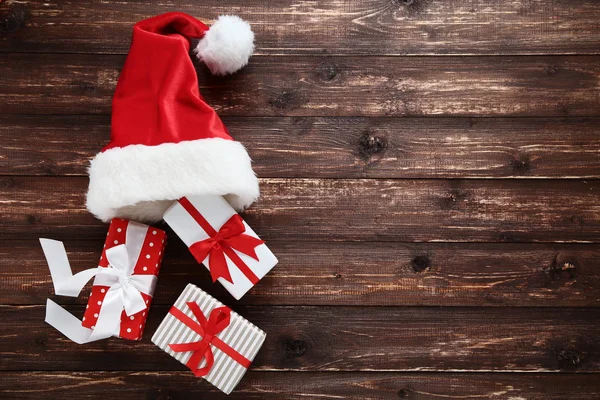 圣诞老人帽子与礼物箱子在棕色木桌 — 图库照片