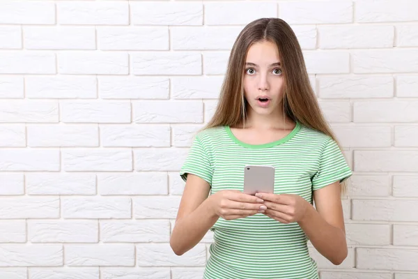 Menina Surpresa Com Smartphone Fundo Parede Tijolo — Fotografia de Stock