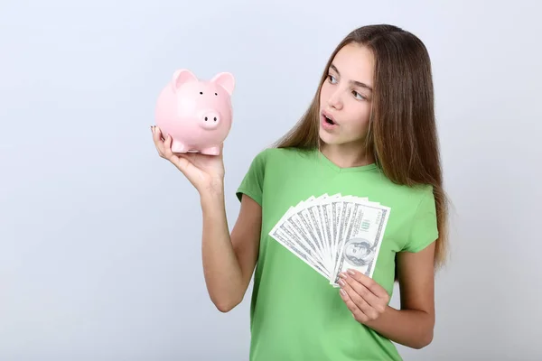 Ung Flicka Håller Rosa Piggybank Och Dollar Sedlar Grå Bakgrund — Stockfoto