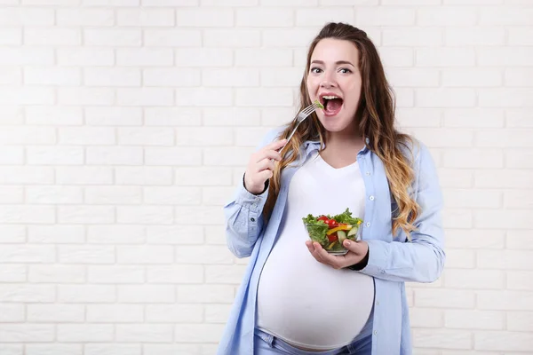 Mooie Zwangere Vrouw Frisse Salade Eten Bakstenen Muur Achtergrond — Stockfoto