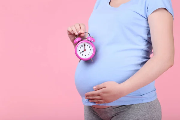 Mujer Embarazada Sosteniendo Reloj Despertador Sobre Fondo Rosa — Foto de Stock