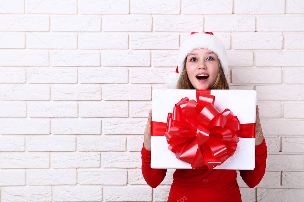 Young girl holding gift box on brick wall background