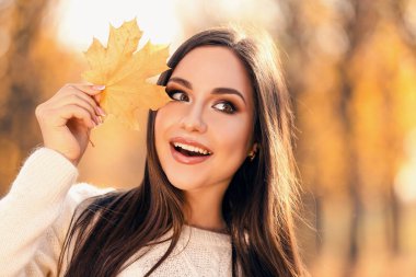 Sonbahar park akçaağaç yaprağı tutan güzel kadın