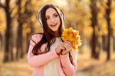 Güzel bir kadınla kulaklık ve kuru Akçaağaç Sonbahar parkta bırakır