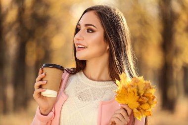 Akçaağaç yaprakları ve kağıt bardak Sonbahar Park ile güzel kadın