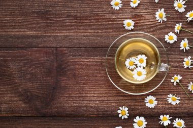 Kahverengi ahşap masa üzerinde papatya çiçeği ile çay