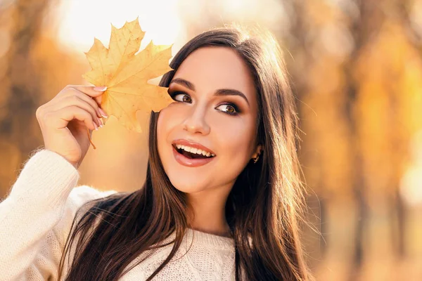 Sonbahar park akçaağaç yaprağı tutan güzel kadın