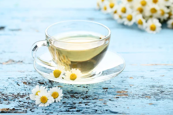 Mavi ahşap masa üzerinde papatya çiçeği ile çay